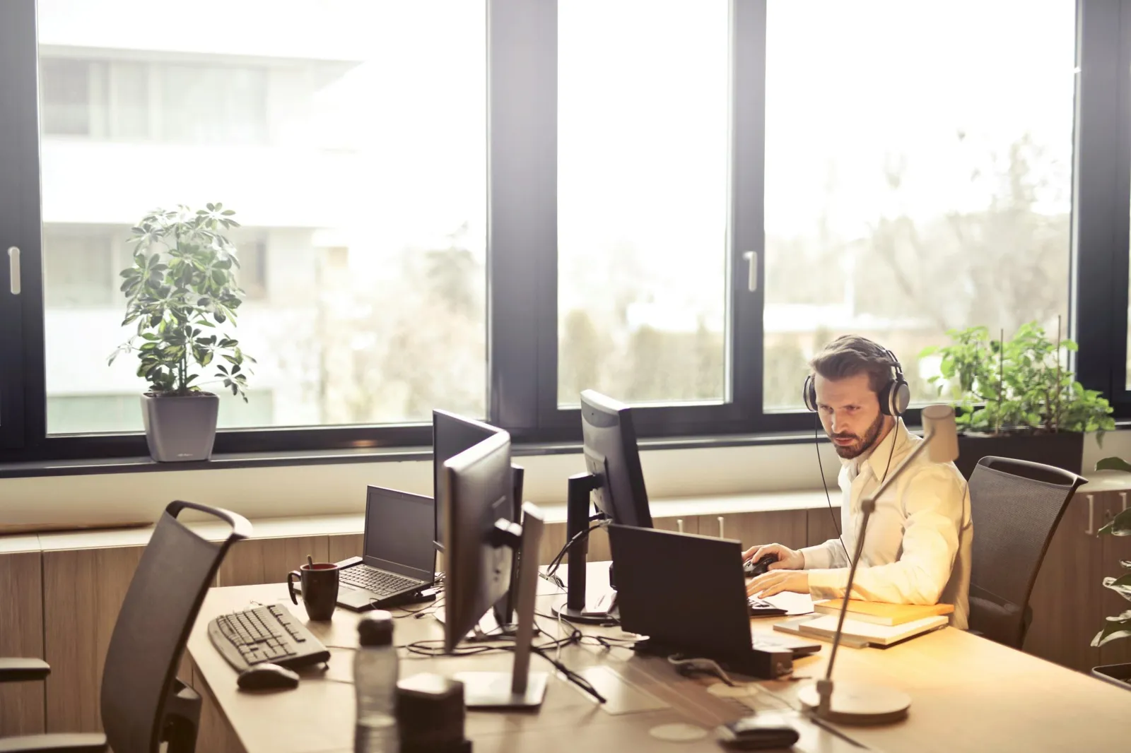 Developer with headphones working at a desk with several screens